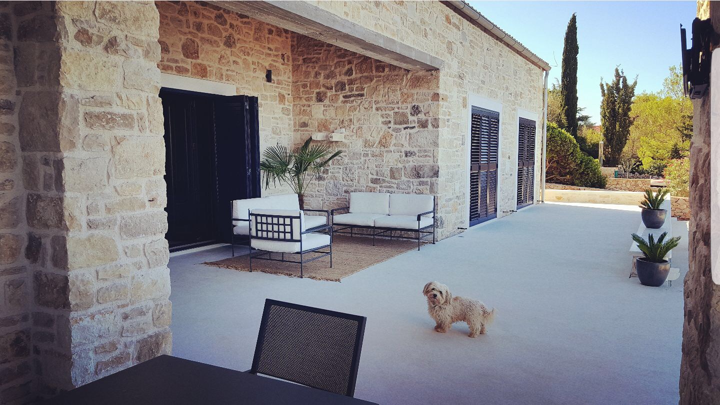 White microcement terrace floor and stone wall house