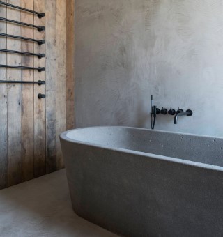 Gray microcement wall and floor. Concrete bathtub.
